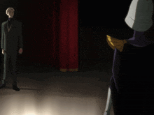 a man in a suit stands next to a person doing a trick