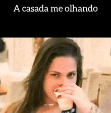 a woman is drinking a glass of milk and covering her nose .
