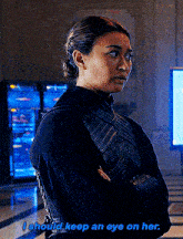 a woman is standing in a room with her arms crossed and says i should keep an eye on her .