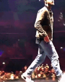a man is dancing on a stage with a crowd watching