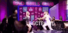 a group of women dancing in front of a sign that says bad girls club