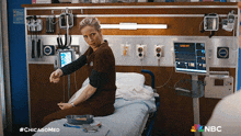 a woman is sitting on a hospital bed with a nbc logo in the corner