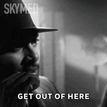 a black and white photo of a man with the words get out of here