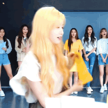 a woman with blonde hair is standing in front of a group of women