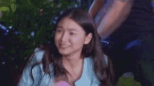 a woman in a blue shirt is making a funny face while sitting in front of a man .