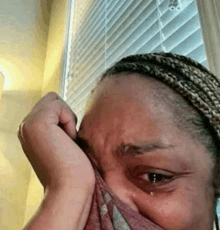 a woman is crying while covering her face with a towel .