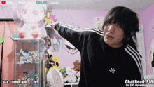 a man in a black adidas sweatshirt is standing in front of a display case