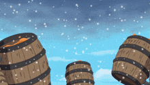 three wooden barrels with a blue sky in the background and snow falling