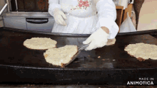 a woman is cooking food on a griddle and the words made in animotica are on the bottom right