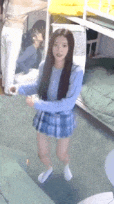a girl in a blue plaid skirt and white socks is standing in a room with bunk beds .