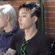 a man wearing a black shirt and green sunglasses is sitting next to another man with white hair