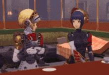 two robots are sitting at a table in a room talking to each other .