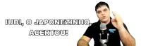 a man stands in front of a microphone with the words " iudi o japonezinho acertou " behind him