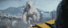 a giant monster is standing in the middle of a city with mountains in the background