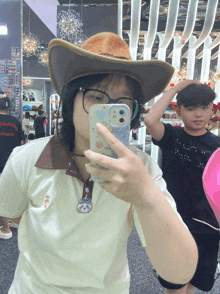 a girl wearing a cowboy hat is taking a selfie