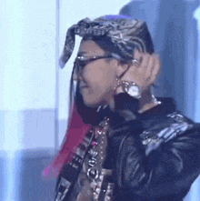 a person wearing a bandana and glasses is adjusting their ear buds .