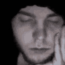 a close up of a person 's face with their eyes closed and their hand on their face .