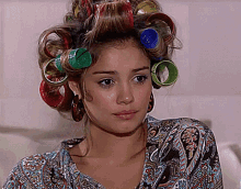 a woman with curlers in her hair is wearing earrings and a paisley shirt