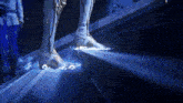 a person 's feet are glowing in the dark with a blue light behind them