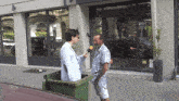 a man talking into a microphone while standing next to a green bin