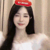a woman wearing a white dress and a red sign on her head is smiling .