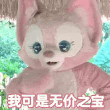a pink stuffed animal with chinese writing on it is standing in the grass .