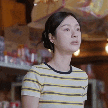 a woman wearing a yellow and white striped shirt is looking up
