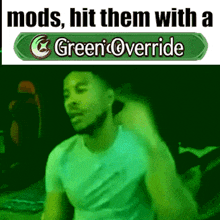 a man in a white shirt is dancing in front of a green sign that says green override