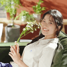 a woman sitting on a green couch holding flowers and smiling