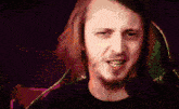 a man with long hair and a beard is looking at the camera