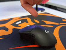 a person is pointing at a black logitech mouse