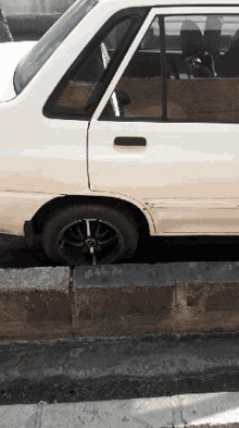 a white car with black wheels is parked on a curb