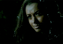 a close up of a woman 's face in the dark with snow falling on her hair .