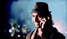a man wearing a hat is talking on his cell phone