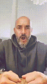 a man with a beard and a hoodie is making a funny face .