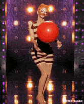 a woman in a striped dress is holding a red balloon in her hands