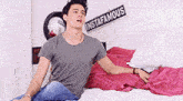a man is sitting on a bed with a sign that says instafamous