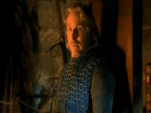 a man is standing in a dark room with a sword hanging on a wall .