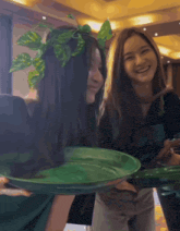 a woman wearing a plant headband holds a green tray