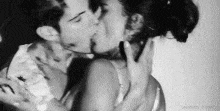 a man and a woman are kissing each other in a black and white photo .