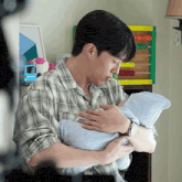 a man in a plaid shirt is holding a baby in his arms in front of an abacus