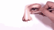 a person is painting a woman 's face with a brush on a piece of paper .