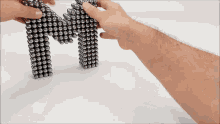 a person is playing with magnetic balls and the letter m is made out of them