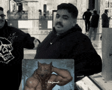 a man in a black hoodie is standing next to a picture of a wolf with muscles