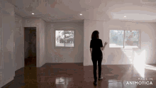a woman stands in an empty room with the words made in animatica on the bottom right