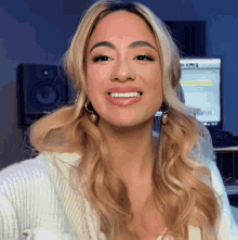 a woman with blonde hair is smiling in front of a computer screen