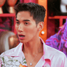 a man wearing a pink shirt and a silver necklace