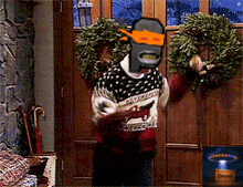 a man wearing a sweater with a horse on it is holding a wreath in front of a door