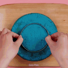a person is cutting a blue cake with an easy plus logo in the upper right corner