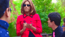 a woman in a red jacket and sunglasses is talking to a man